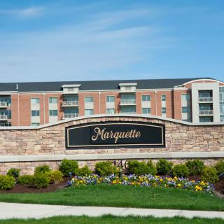 A modern residential apartment complex with neatly landscaped grounds and a prominent entrance sign.