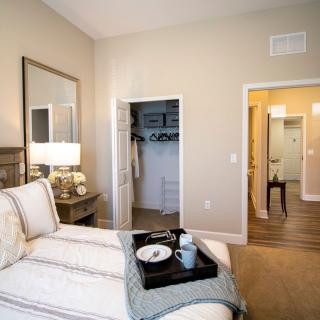 A cozy bedroom with a neatly made bed, a tray with cups, and a well-organized closet.