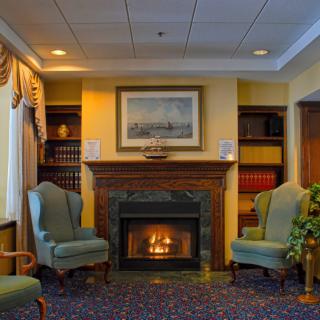 A cozy living room featuring a fireplace, surrounded by armchairs and bookshelves.