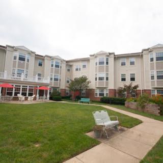 A view of a residential apartment complex with well-maintained lawns and a sidewalk.