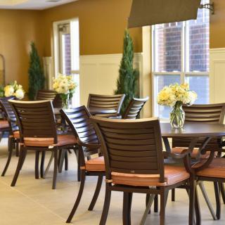 An elegant dining area featuring neatly arranged tables and chairs, decorated with vases of flowers.