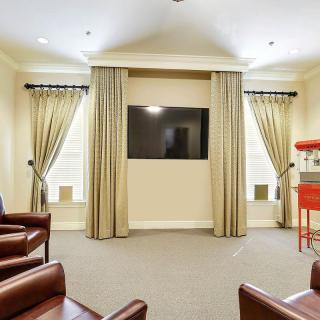 A cozy home theater setup with a wall-mounted TV, comfortable seating, and a popcorn machine.