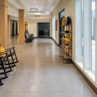 A modern hallway with rocking chairs and large windows.