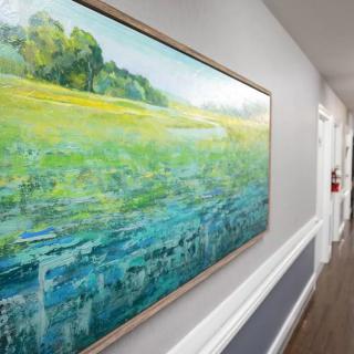 A vibrant landscape painting displayed in a hallway.