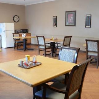 A cozy dining area with tables and chairs, featuring a small kitchen space with a refrigerator and microwave.