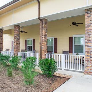 A charming residential porch with brick columns and landscaping.