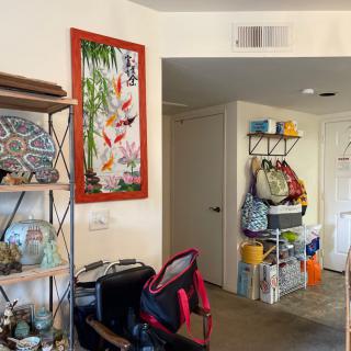 A cozy living room corner with shelves, colorful artwork, and organized storage.