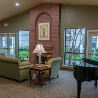 A cozy living room with a piano, sofas, and a fireplace.