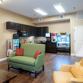 A modern lounge area with a kitchenette, featuring comfortable seating and well-equipped appliances.