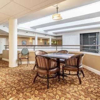 A cozy lounge area with a table and chairs, featuring warm lighting and patterned carpet.
