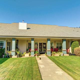 A spacious house with a large porch and well-maintained lawn on a sunny day.