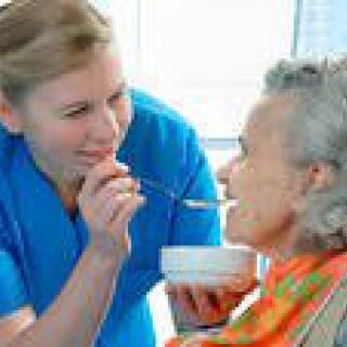 A caregiver assisting an elderly person with a meal.