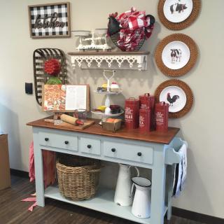 A rustic kitchen setup with decorative shelves, plates on the wall, and condiments on a wooden table.