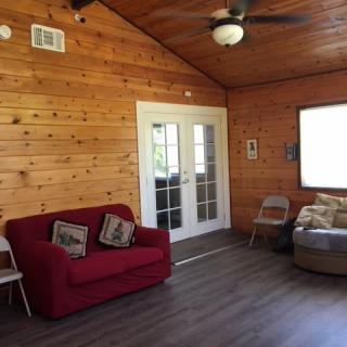 A cozy living room with wood paneling, a red sofa, and a ceiling fan.