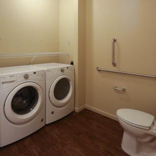 A room featuring a washer and dryer next to a toilet.