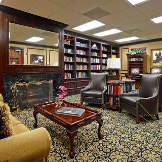 A cozy library with elegant bookshelves, a fireplace, and comfortable seating.