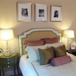A cozy bedroom with stylish decor, featuring a neatly made bed, two lamps, and framed wall art above the headboard.