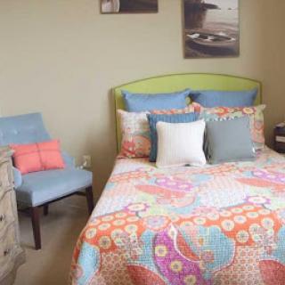 A vibrant and inviting bedroom featuring a colorful quilt and decorative pillows.