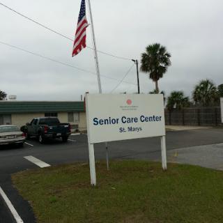 A view of the Senior Care Center, showcasing a flag and surrounding palm trees.