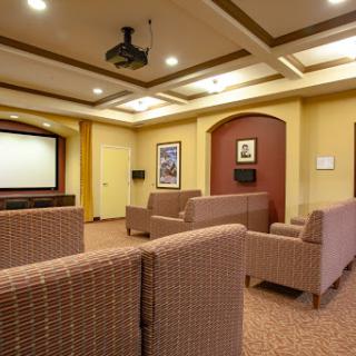 A cozy lounge area featuring comfortable seating and a projector screen, perfect for relaxation and entertainment.