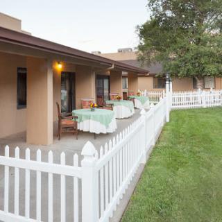 A charming outdoor view of a residential area featuring a white picket fence and cozy patios.