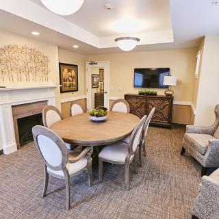 A cozy dining room with a round table, elegant chairs, and a fireplace, adorned with stylish decor and art.