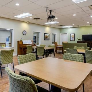 A spacious dining or community room with multiple tables and chairs, well-lit and neatly arranged.