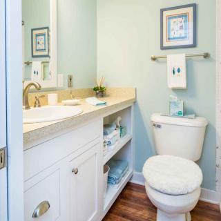 A cozy and well-organized bathroom with light colors and simple decor.