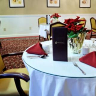A neatly set dining table with a menu and poinsettia centerpiece in a restaurant.