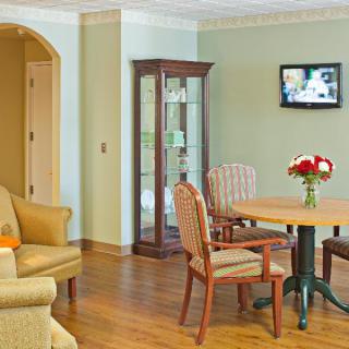 A cozy living room with a table, chairs, sofa, and a wall-mounted TV.