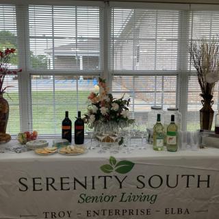 A table display at Serenity South Senior Living showcasing wine bottles and decorative items.
