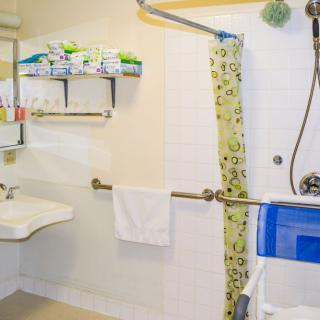 A clean and organized bathroom with a shower, sink, and storage shelves.