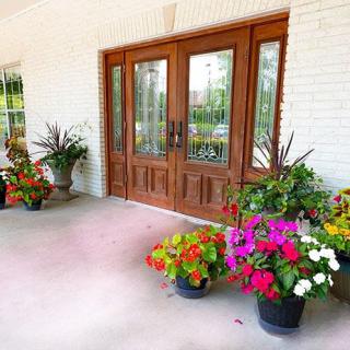 A welcoming front porch adorned with vibrant potted flowers and a wooden double door.