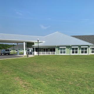 A modern building with a large green lawn under a clear blue sky.