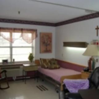 A hospital room with a bed, chair, and table by the window.