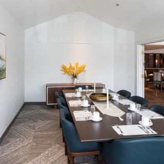 A modern dining room with a large table set for a meal, featuring elegant decor and a vase of yellow flowers.