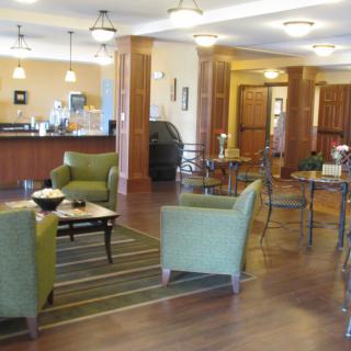 A modern and cozy cafe with green chairs and wooden tables.