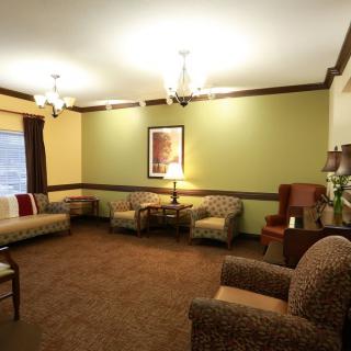 A cozy living room with sofas and armchairs, decorated with a chandelier and wall art.