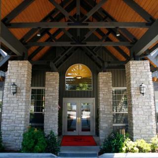 A welcoming building entrance with stone pillars and a wooden roof.