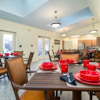 A modern dining area with neatly arranged wooden tables and red tableware.