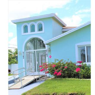 A charming blue house with a well-maintained garden and vibrant flowers at the entrance.