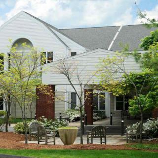 A white building surrounded by trees and benches in a landscaped area.