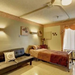 Cozy bedroom with a bed and sofa, featuring warm lighting and inviting decor.