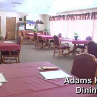 A spacious dining area with multiple tables and chairs, labeled as Adams Hall Dining.