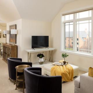 A modern living room with sleek furniture and a large window, featuring a TV and stylish decor.