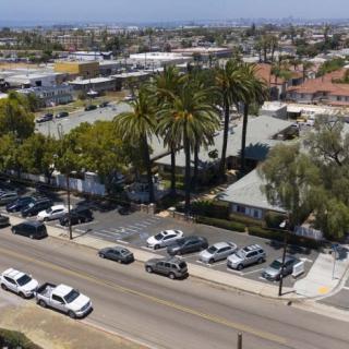 Aerial view of a suburban area with a parking lot, palm trees, and surrounding buildings.