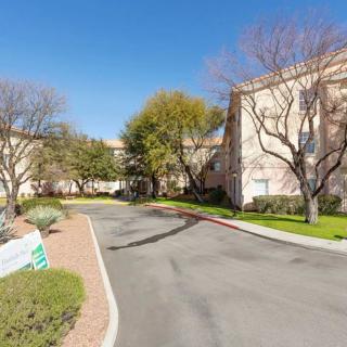 A quiet road curves through a landscaped area with trees and buildings on a clear day.