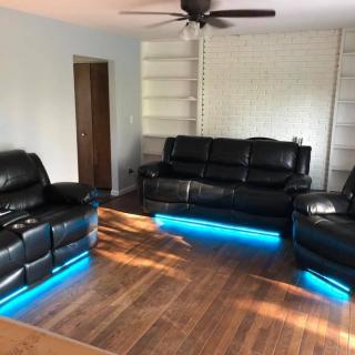Modern living room with leather couches and LED lighting.