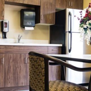 A cozy kitchen corner with wooden cabinets, a refrigerator, and a dining chair.