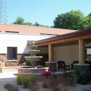 A serene outdoor patio area featuring a multi-tiered fountain surrounded by greenery and seating.
